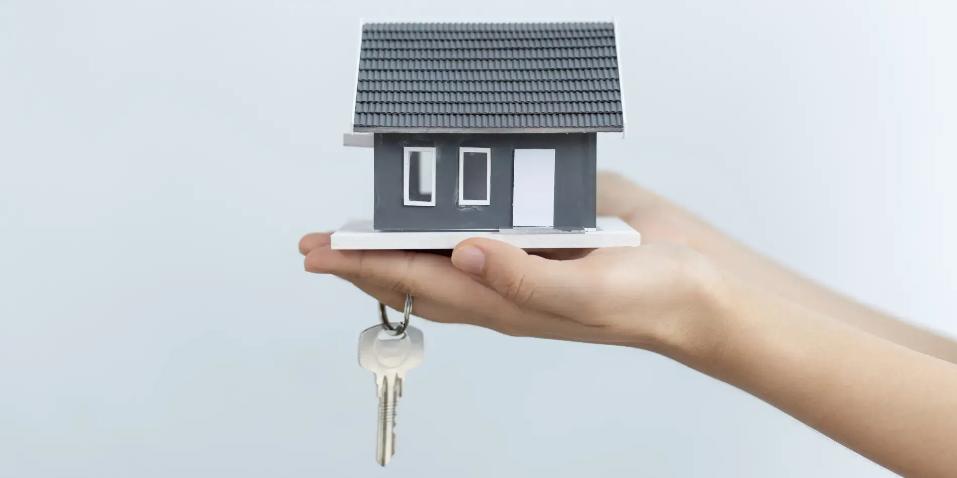 Hand holding model house and key