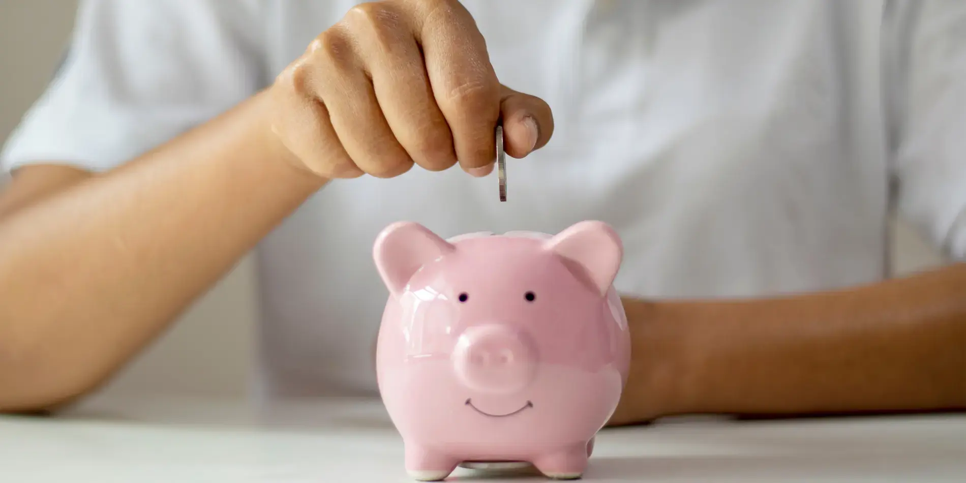 hand putting coin in piggy bank