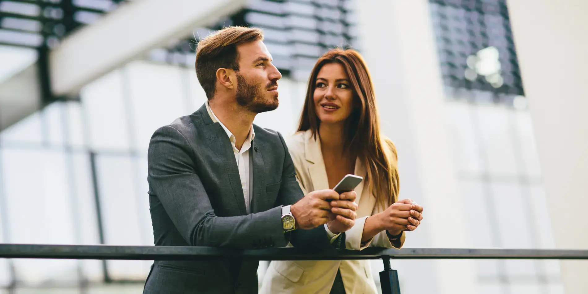 Man in grey suit and woman in beige blazer chatting